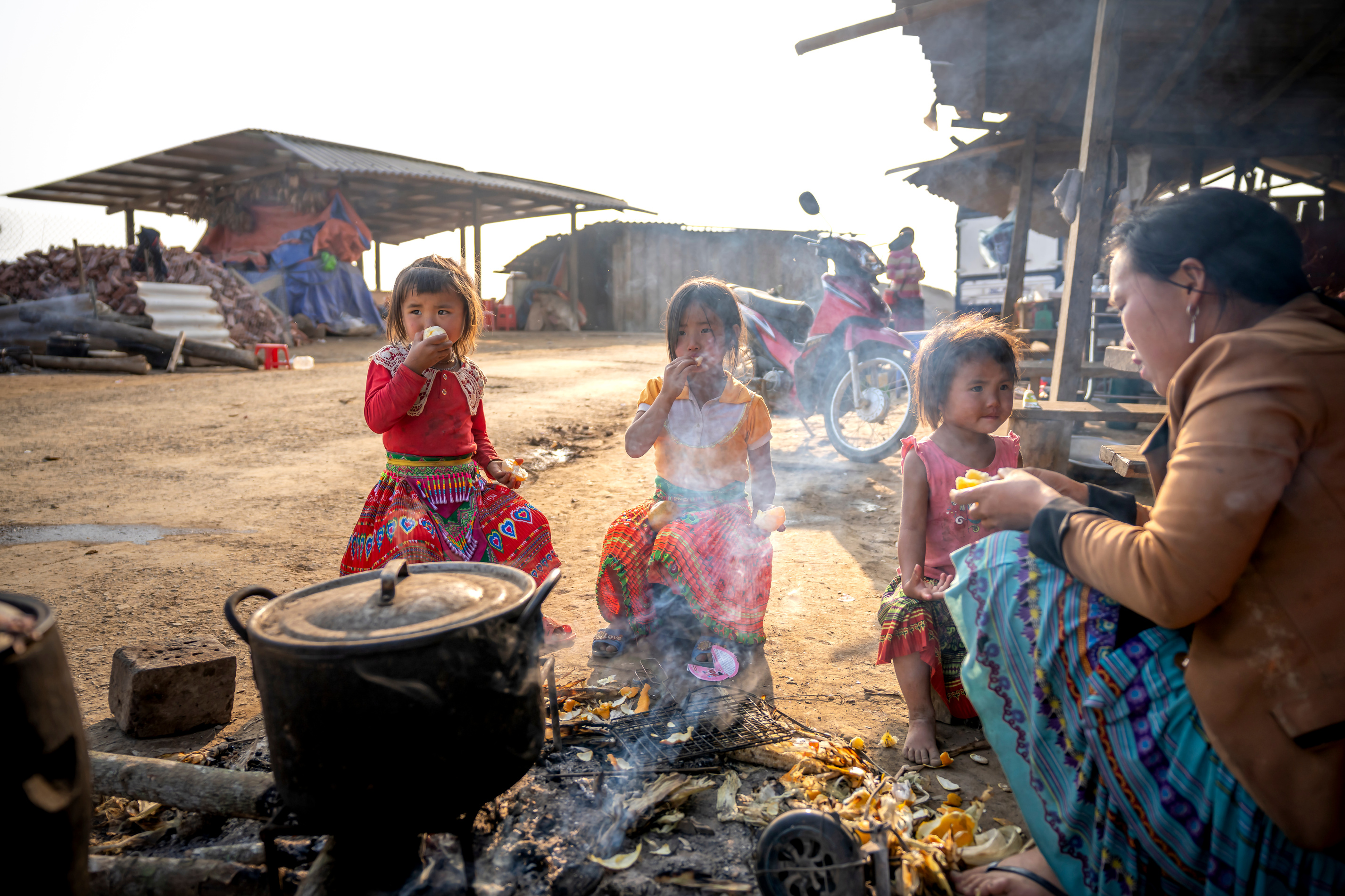 Photo of Woman Cooking While Sitting Near Her Children